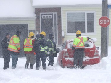 OTTAWA - Jan 17 2022 -. A group of construction workers help dig out a car on Rockhurst Street in Ottawa Monday.