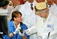 Queen Elizabeth II, wearing a white protective coat (R), is shown a new product, at the final testing before packaging test area during her tour of the RIM (Research In Motion) factory that produces the Blackberry mobile communications handset, on July 5, 2010 in Waterloo, Canada.