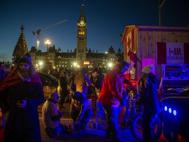 OTTAWA -- The crowd lessened as the sun set, but many people stayed out getting closer to small fires and heaters to stay warm in the cold temperatures.