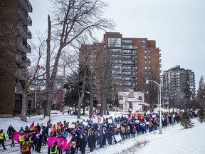 A long line of Ottawa-area residents opposed to the truck convoy protest downtown walks along the Queen Elizabeth Driveway on Saturday.