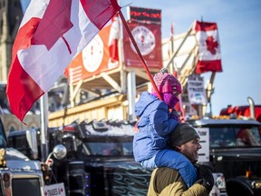 A young child sits on the shoulders of a protester in downtown Ottawa on Sunday.