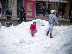 Zwei Kinder spielen am Samstag in einer Schneewehe in der Sparks Street.
