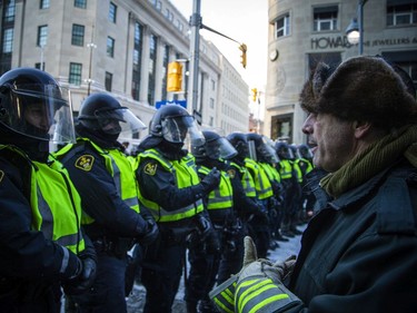 A protester gets face-to-face with a line of Ontario Provincial Police officers on Bank Street near Sparks Street on Saturday evening.