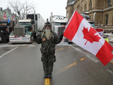 The trucker protest entered its 12th day in the capital Tuesday, a day after a judge granted an injunction against honking in downtown Ottawa. A supporter of the convoy demonstration waves the Canadian flag in front of Parliament Hill, downtown Ottawa on February 08, 2022.