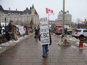 The Fairmont Chateau Laurier hotel, left, stands in the background as a protester walks east on Wellington Street on Thursday.