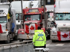 A police officer stands alone near trucks participating in the blockade of downtown streets near the Parliament building Wednesday.