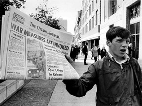A newsboy holds up a newspaper reporting the invoking of the War Measures Act by Pierre Trudeau on Oct. 16, 1970.