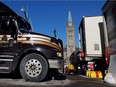A protester receives gas cans from the back of a vehicle in front of Parliament Hill Monday as truckers and supporters continue their occupation of downtown Ottawa.