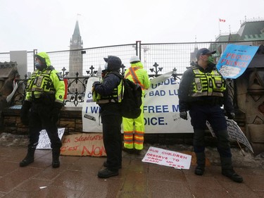 Police officers keep a watchful eye while workers secure fences, as truckers and supporters continue to protest coronavirus disease (COVID-19) vaccine mandates, in Ottawa, Ontario, Canada, Feb. 17, 2022.