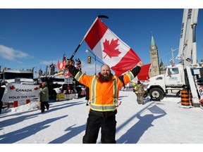 A man holds a Canadian flag in front of Parliament Friday morning. Others were shoring up snowbanks near their barricades. it made no sense — but what has made sense in this occupation?