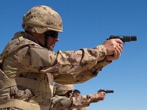 Members of the Military Police and the Area Security Force practice firing the Browning 9mm pistol from the kneeling position at the weapons range during Operation IMPACT on March 4, 2015.   Photo: OP Impact, DND