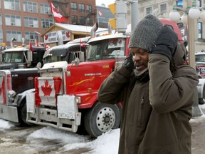 A man covers his ears while passing honking trucks parked on Wellington Street this week.