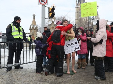 Anti-vaccine mandate protesters and truckers protesting their eighth day in Ottawa Friday. Liam, who is wearing a billboard, gets a hug from a supporter Friday afternoon. Liam was out protesting on Wellington Street asking for support to have the choice with his own body.