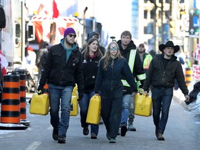 A group of protesters carry empty gas cans in downtown Ottawa Monday.