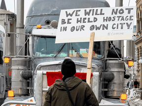 A man in Ottawa holds up a sign urging 'Freedom Convoy' participants to go home on February 2, 2022.
