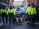 Anggota Kepolisian Ottawa menemani petugas Ottawa By-Law saat mereka mengeluarkan tiket parkir dan denda selama protes 'Konvoi Kebebasan' di pusat kota.