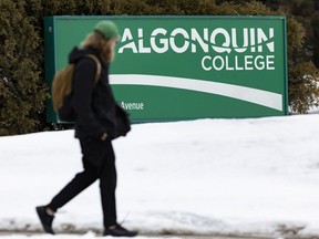 Un étudiant passe devant une enseigne du Collège Algonquin sur le campus de Woodroffe.