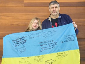 Iryna and Pavlo Aksentiev came to Ottawa from Kyiv 21 years ago. The flag they're holding was signed by veterans of Ukraine's 72nd Mechanized Brigade.