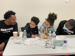Nassim Ashford, left, and Macire Aribot, co-founders of NoirUnited International, keep children occupied at the RedCross information center in Paris, France.