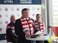 Jeff Hunt (left), President and Strategic Partner of Atlético Ottawa, Andrii Bukvych, Chargé d'Affaires at the Ukrainian Embassy (middle) and Jim Watson (right) announce an initiative in support of humanitarian aid for Ukraine in Ottawa, March 28, 2022.