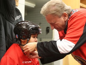 Eugene Melnyk ties the helmet of Eh Nay Soe Kyu of D. Roy Kennedy school during the 15th annual Eugene Melnyk Skate for Kids at Canadian Tire Centre, Dec. 20, 2018.