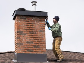 Nature's Way Property Services owner Todd Babin does some caulking to animal-proof a chimney at a client's house on March 23, 2022.