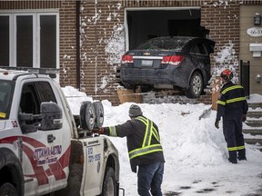 Tow truck removes a car from inside of a rowhouse on Heney Street in Lowertown Saturday afternoon.