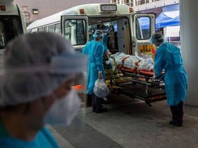 A patient is transferred onto a bus outside Queen Elizabeth Hospital in Hong Kong as the government announced the hospital will be used only for COVID-19 patients, , March 10, 2022.