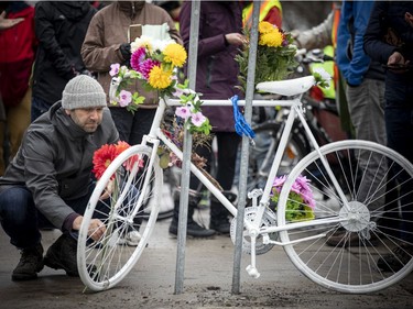 A group of people gathered at the corner of North River Road and Donald Street, where a cyclist was struck and killed last week. The group, led by Bike Ottawa, installed a ghost bike at the corner to pay tribute to the woman whose life was lost. Dave Robertson a board member with Bike Ottawa, placed flowers on the ghost bike on Sunday, March 20, 2022.