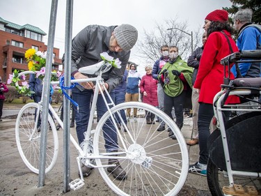 A group of people gathered at the corner of North River Road and Donald Street, where a cyclist was struck and killed last week. The group, led by Bike Ottawa, installed a ghost bike at the corner to pay tribute to the woman whose life was lost. Dave Robertson a board member with Bike Ottawa, placed flowers on the ghost bike on Sunday, March 20, 2022.