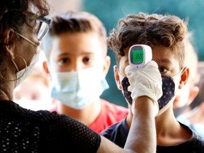 File: A pupil has his temperature checked at school.