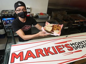 Mark Fernandez, owner of Markie’s Smoked Meat, poses for a photo with his mask on at his business in Ottawa Wednesday. Fernandez and his staff will stay masked after restrictions are lifted.