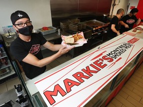Mark Fernandez, owner of Markie's Smoked Meat, poses for a photo with his mask on at his business in Ottawa Wednesday. Fernandez and his staff will stay masked after restrictions are lifted.