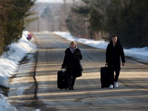 Would-be asylum seekers walk with their luggage on Roxham Road before crossing the U.S.-Canada border into Canada in Champlain, N.Y. in pre-pandemic days.