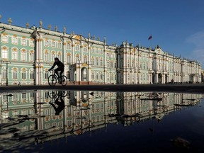 A cyclist rides past the State Hermitage Museum in Saint Petersburg, Russia.