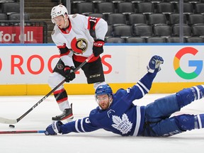 Drake Batherson #19 of the Ottawa Senators gets set to fire a puck away from a falling T.J. Brodie #78 of the Toronto Maple Leafs during an NHL game at Scotiabank Arena on January 1, 2022