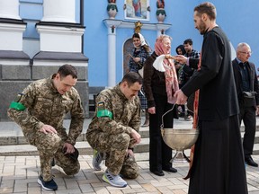 Ukrainian soldiers kneel as they receive blessings the St. Michaels Golden-Domed Cathedral on April 24, 2022 in Kyiv, Ukraine. Orthodox Easter celebrations come as Ukraine marks two months since the start of Russia's February 24 invasion, a war that has killed untold thousands of civilians and soldiers.