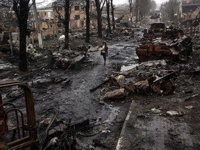 A woman walks amid destroyed Russian tanks in Bucha, in the outskirts of Kyiv, Ukraine, on April 3, 2022. A mass grave has been discovered in Bucha, where bodies were also found scattered in the streets in the wake of the retreat of Russian forces.