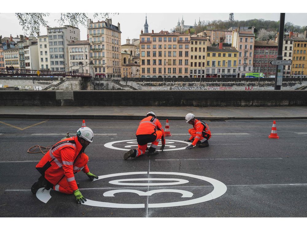 City employees install road signs matching the new speed limit of 30 kilometres an hour within the city perimeter in Lyon, France, in March. More and more cities worldwide are slowing things down. 
