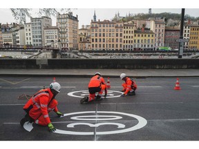 City employees install road signs matching the new speed limit of 30 kilometres an hour within the city perimeter in Lyon, France, in March. More and more cities worldwide are slowing things down.