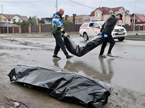 CAPTION ADDITION - Communal workers carry body bags in the town of Bucha, not far from the Ukrainian capital of Kyiv on April 3, 2022. US and NATO leaders voiced shock and horror at new evidence of atrocities against civilians in Ukraine, and warned that Russian troop movements away from Kyiv did not signal a withdrawal or end to the violence.