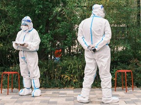 Community volunteers wearing personal protective equipment stand during a test for the COVID-19 coronavirus in a compound in shanghai.