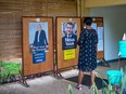 A woman looks at posters before casting a ballot in France's second round of Presidential elections, at the French Embassy in Bangui on April 24, 2022. - French voters cast their ballots for the presidential run-off between centrist incumbent Emmanuel Macron and his far-right challenger Marine Le Pen, who is hoping to prove opinion polls wrong and become the first woman to win the country's highest public office.