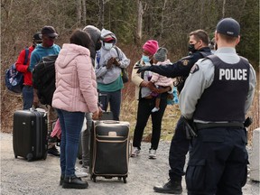 Asylum seekers talk to a police officer as they cross into Canada from the U.S. border near a checkpoint on Roxham Road near Hemmingford, Quebec, Canada April 24, 2022.