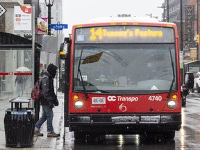 A passenger embarks on an OC Transpo city bus at the corner of Gladstone and Elgin Street.
