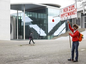 A man holds a sign reading "No to mandatory vaccination" near the Reichstag building, the seat of Germany's lower house of parliament, on the day the Bundestag is set to vote on several proposals introducing or blocking a coronavirus disease (COVID-19) vaccine mandate for the general population, in Berlin, Germany, April 7, 2022.