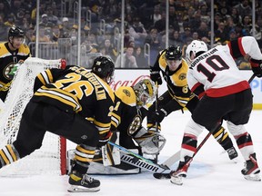 Boston Bruins goaltender Jeremy Swayman (1) makes a save while Ottawa Senators left wing Alex Formenton (10) and center Marc McLaughlin (26) look for a rebound at TD Garden, Thursday.