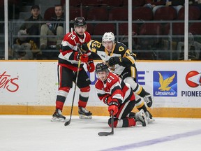 Alex Johnston (21) of the Ottawa 67's and Nathan Staios (44) of the Hamilton Bulldogs battle for the puck in front of Ottawa's Tyler Boucher (13) during an Ontario Hockey League game in Ottawa on Friday, April 8, 2022.