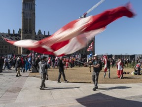Un manifestant agite un drapeau canadien géant sur la colline du Parlement lors de l'événement «Rolling Thunder Ottawa» samedi après-midi.