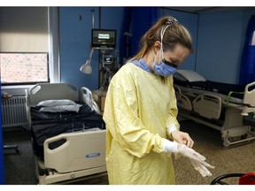 Registered nurse Courtney Benoit dons gloves and other personal protective equipment before tending to a patient  in the special-care unit of Campbellford Memorial Hospital in Campbellford, Ont.